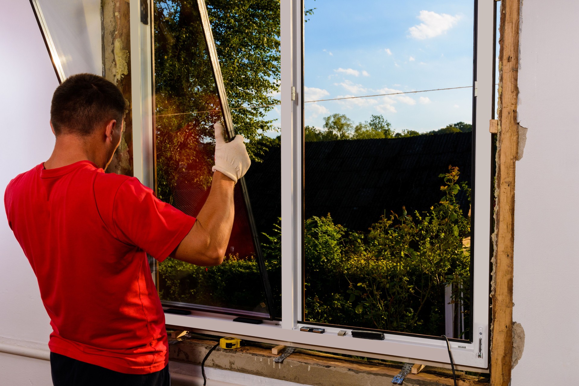 The worker inserts glass into the window frame, triple glazing of the plastic window, insulation and insulation.